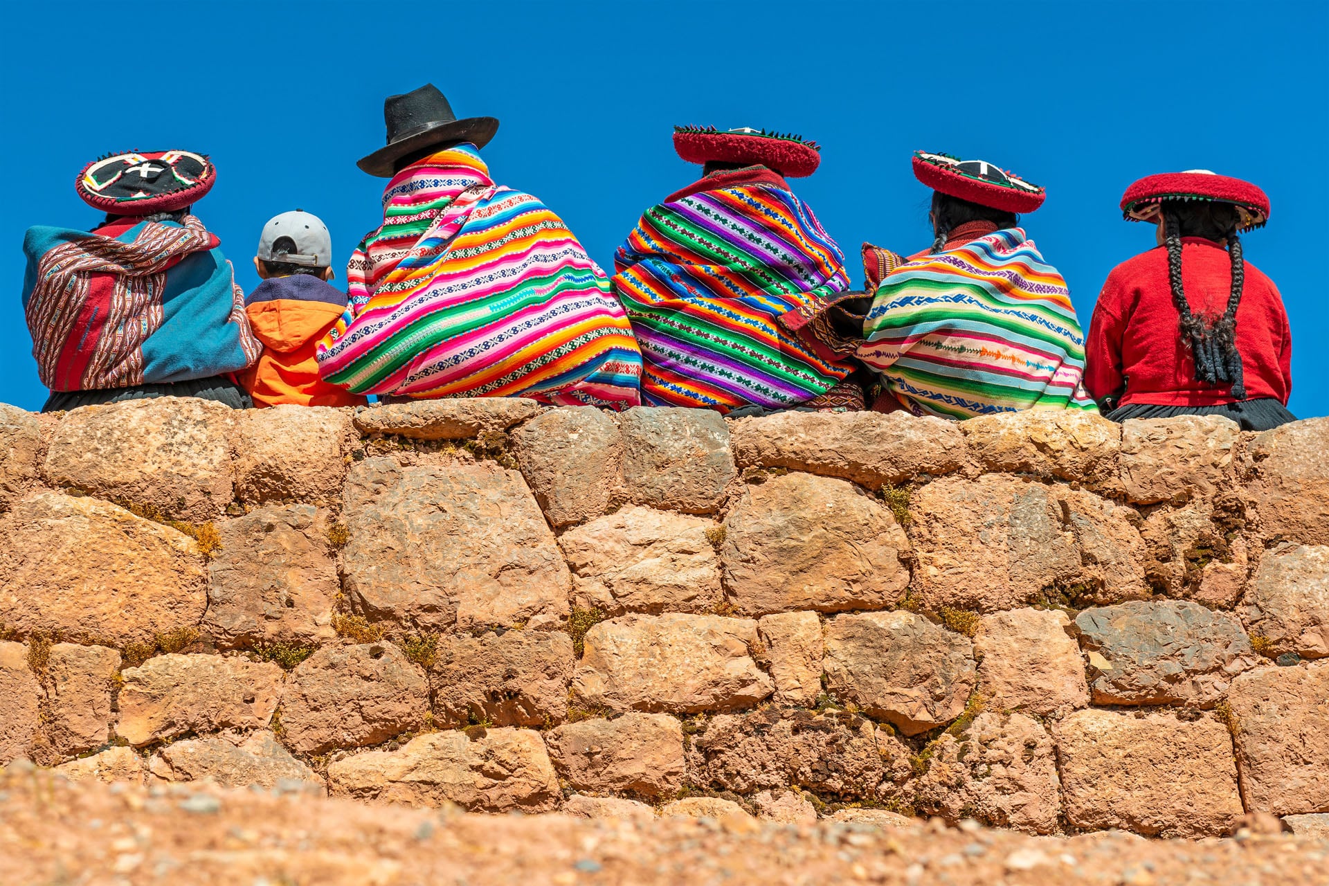 Femmes quechuas en vêtements traditionnels assises sur un mur inca, Pérou
