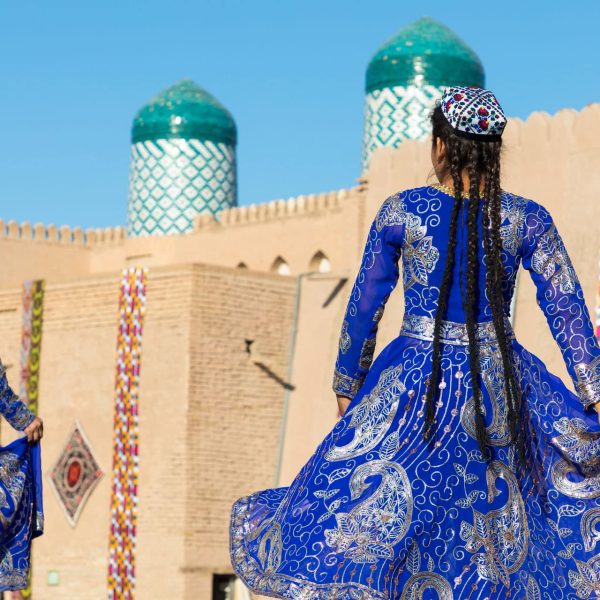 Danseuse en tenue traditionnelle devant les coupoles de Khiva, Ouzbékistan